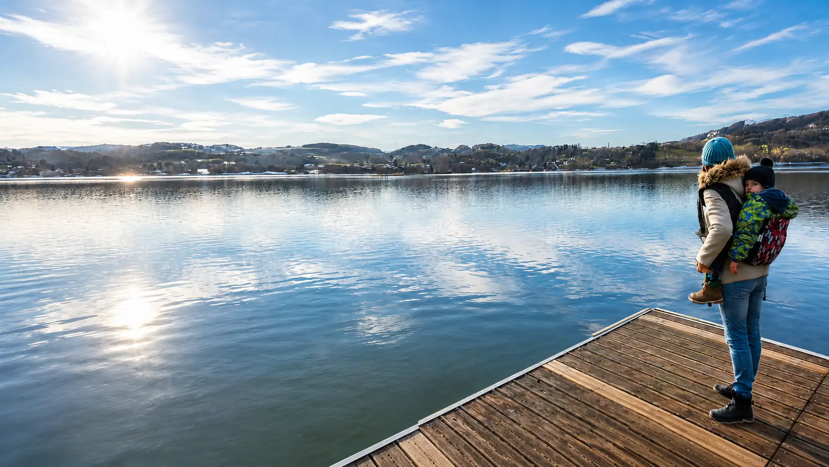 Parent portant un enfant face a un lac